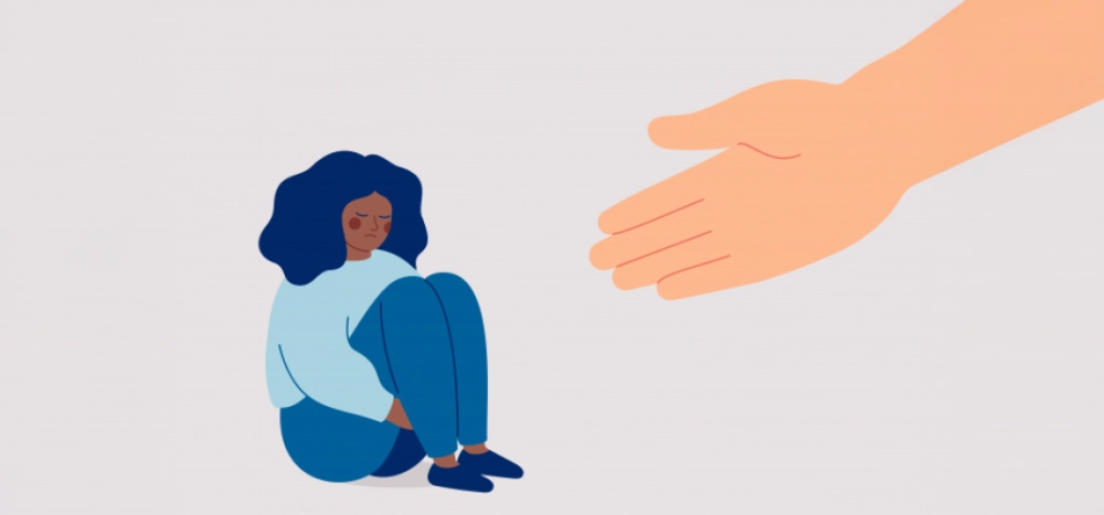 Femme triste assise, main tendue en signe de soutien